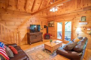 a living room with a couch and a television in a cabin at Updated Cabin Mins from Downtown West Jefferson- Hot Tub, Porches, Dogs OK in West Jefferson