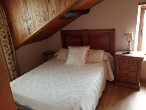a bedroom with a white bed with a wooden headboard at Casa De la Agüera in Busto