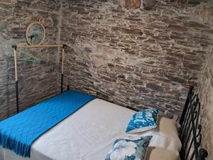 a bed in a room with a brick wall at AL Rossadas Margurisse in Benfeita
