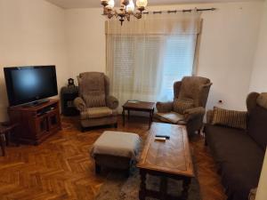 a living room with a couch and chairs and a tv at Sweet Dream Rooms in Podgorica