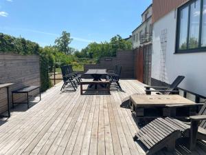 a wooden deck with tables and chairs on a building at Udda boende med wow-känsla och spabad på terrassen in Löderup