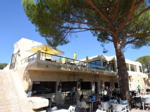 a building with a tree and people sitting at tables at Mobil home - 8 couchages avec lit bébé - ECRIN DE SÉRÉNITÉ - Camping TIKAYAN 5 étoiles - Le Muy in Le Muy