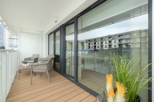 ein Balkon mit Glastüren und einem Tisch und Stühlen in der Unterkunft Polanki Aqua Stylowy Apartament 300 m od Plaży by Noclegi Renters in Radzikowo