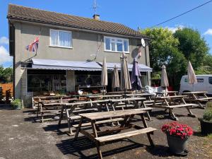 a group of wooden tables and umbrellas in front of a building at Wookey Holiday Flat in Wookey