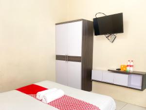 a room with a bed with a cabinet and a tv at Hotel O Kate'el Inn in Banyuwangi
