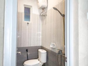 a bathroom with a toilet and a shower at Hotel O Kate'el Inn in Banyuwangi