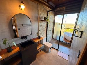 un bagno con un water, un lavandino e uno specchio di Chalé Candombá a São Jorge Altre 11 foto