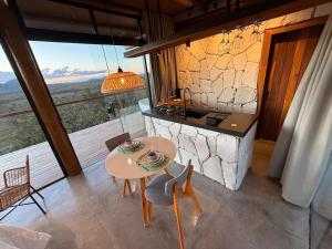 a small table and chairs in a room with a stove at Chalé Canela de Ema in Sao Jorge