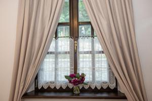 a window with curtains and a vase with flowers at Odaile Brancovenesti -Maldaresti in Măldăreşti