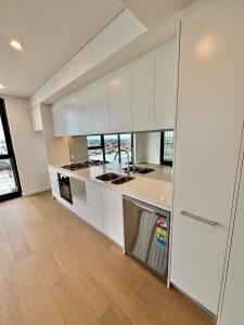 バンクスタウンにあるThe Luxury Penthouse at Spring Squareの白いキャビネットと木製の床を備えたキッチン