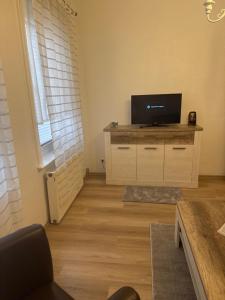 a living room with a flat screen tv on a dresser at Apartments Mykonos in Braunlage