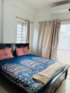 - une chambre avec un lit avec une couette bleue et 2 fenêtres dans l'établissement Holastay, à Jāmb