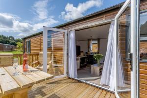an open sliding glass door on a deck with a table at Clumber Park Lodges in Worksop +10 photos