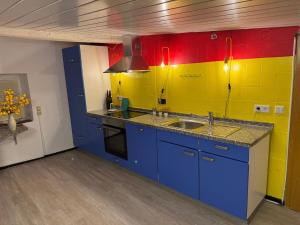 a kitchen with blue cabinets and yellow and red walls at Kleines Wiesel in Gladbeck