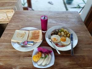 a wooden table with two plates of breakfast food at Gamat Sunset Cottage and Resto in Nusa Penida +23 photos