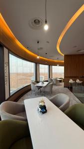 a room with a table and chairs and a large window at Artama Hotel in Unayzah