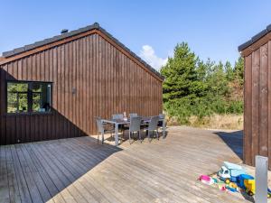 a wooden deck with a table and chairs in front of a building at Holiday Home Heidi - 1km from the sea by Interhome in Mølby +31 photos