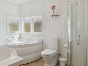 a white bathroom with a tub and a toilet and a sink at Holiday Home Fenja - 1-2km from the sea by Interhome in Marielyst
