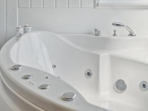 a white bath tub with a sink in a bathroom at Holiday Home Fenja - 1-2km from the sea by Interhome in Marielyst +6 photos