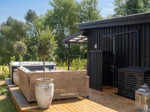 a black building with a deck with a hot tub at Holiday Home Thorlak - 860m from the sea by Interhome in Marielyst