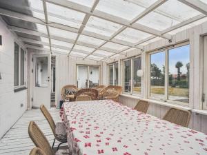a dining room with a table and chairs on a porch at Holiday Home Janna - 75m from the sea by Interhome in Gørlev