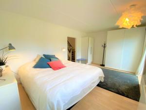a bedroom with a white bed with red and blue pillows at Apartment Bena - 150m from the sea by Interhome in Dronningmølle