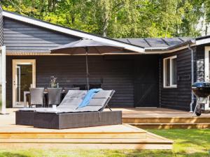 a patio with an umbrella and chairs and a grill at Holiday Home Heidel - 1-1km from the sea by Interhome in Nyrup