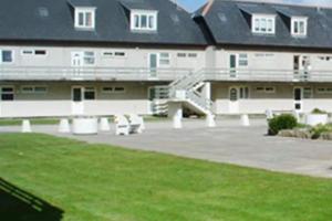 a large building with a park with benches in front of it at By the Beach Perranporth, Truro, cornwall in Perranporth