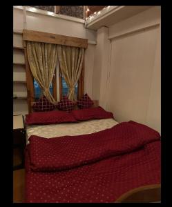 a bedroom with a bed with red sheets and a window at Nupurs BnB in Shillong