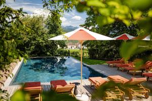 a swimming pool with lounge chairs and an umbrella at Castel Sallegg Suites Adults only in Caldaro