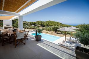 a patio with a table and chairs and a swimming pool at Medows Luxury Villa in Keri