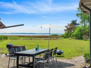a wooden table with chairs and an umbrella at Holiday Home Vemund - 100m to the inlet by Interhome in Vig