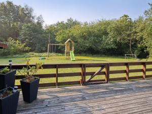 eine Holzterrasse mit einem Spielplatz im Hintergrund in der Unterkunft Holiday Home Elif - 30km from the sea by Interhome in Toftlund