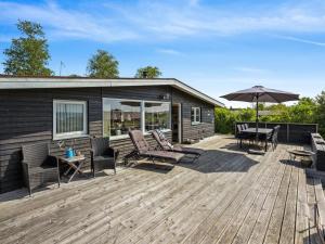 a wooden deck with chairs and an umbrella at Holiday Home Thrugils - 200m from the sea by Interhome in Haderslev