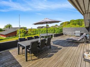 a wooden deck with a table and an umbrella at Holiday Home Thrugils - 200m from the sea by Interhome in Haderslev