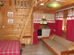 a bedroom in a log cabin with red curtains at le chalet in Névy-lès-Dole