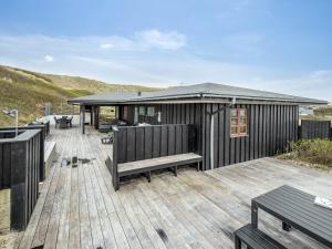 a wooden deck with a house with a bench at Holiday Home Eyla - from the sea by Interhome in Hvide Sande