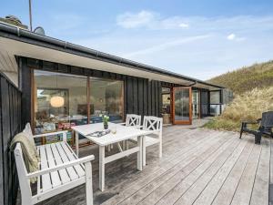 a deck with a white table and chairs on a house at Holiday Home Eyla - from the sea by Interhome in Hvide Sande