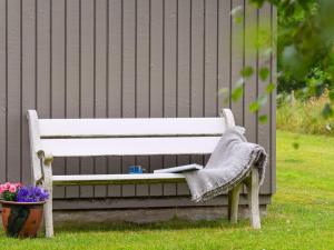 a white bench sitting in the grass with a pot of flowers at Holiday Home Imre - 300m from the sea by Interhome in Glesborg
