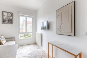 a white living room with a table and a tv at Mykeypers- Design & Cosy Apartment 2P - Malakoff 25 in Malakoff