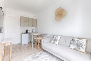 a white living room with a couch and a kitchen at Mykeypers- Design & Cosy Apartment 2P - Malakoff 25 in Malakoff