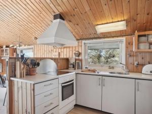 a kitchen with white cabinets and a wooden ceiling at Holiday Home Tianna - 500m from the sea by Interhome in Pandrup