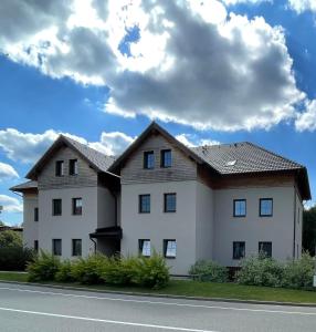 a large white house with a roof at Apartmán U Merlina in Deštné v Orlických horách
