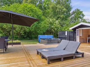 a patio with a couch and an umbrella and a grill at Holiday Home Tia - 1-4km from the sea by Interhome in Sæby