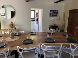 une salle à manger avec une table en bois et des chaises blanches dans l'établissement Maison de la tuilière hautes alpes piscine et boulodrome 12 personnes, à Saléon