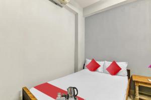 a bedroom with a white bed with red pillows at Hotel O Ganpati in Patna