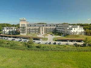 a large building with cars parked in a parking lot at Strandlounge - 5 Sterne-Wohnung mit XXL-Balkon, Wellness & Boddenblick in Wustrow