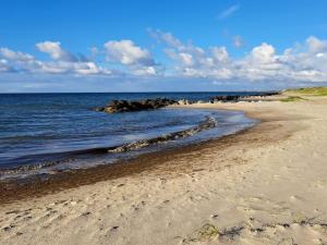 a sandy beach with rocks in the water at Holiday Home Falk - 900m from the sea by Interhome in Skagen