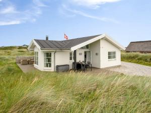 a small white house with a table in a field at Holiday Home Elfi - 700m from the sea by Interhome in Ringkøbing