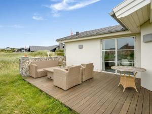 a wooden deck with a table and chairs on it at Holiday Home Elfi - 700m from the sea by Interhome in Ringkøbing +24 photos